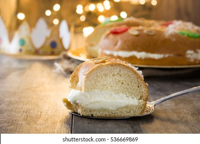 Spanish typical epiphany cake "Roscon de Reyes", and christmas lights on wooden background
