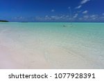 Spanish Wells, Eleuthera, Bahamas - Bright white sand beach and clear green and blue water with a small classic sailboat anchored offshore