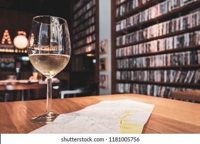 Spanish White Wine And A Map In A Cozy Bar On Wooden Table With Dvd And Book Shelves