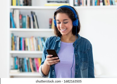 Spanish Young Adult Woman Listening To Podcast Indoors At Home