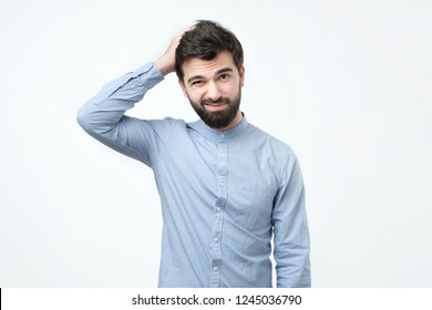 Spanish young man with black beard thinking, scratching his head. I am not sure or who know concept. I am not an expert in this matter. - Shutterstock ID 1245036790
