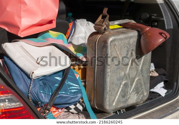 a spare jerrycan in a messy car boot along with\
personal luggage