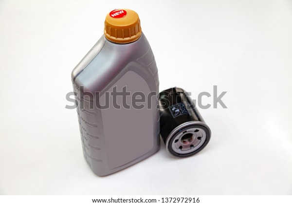 Spare part for car engine  filter for cleaning\
dust and dirt with one liter bottle or can of lubricant on a white\
isolated background. Maintenance and oil change in auto service\
industry.