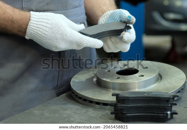 Spare parts. A brake disc and a set of brake pads.\
Close-up. Inspection of spare parts during the repair of the\
suspension of the car.