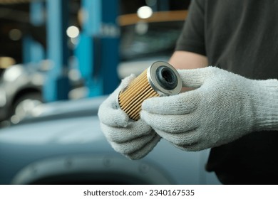 Spare parts. Car maintenance in a car service. An auto mechanic holds a new oil filter in his hands. Monitoring of the technical condition of the filter before installation. - Powered by Shutterstock