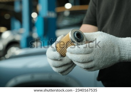 Spare parts. Car maintenance in a car service. An auto mechanic holds a new oil filter in his hands. Monitoring of the technical condition of the filter before installation.