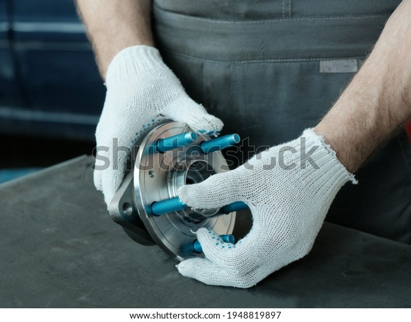 Spare parts for cars. Hub\
bearing close-up. A mechanic in the service center inspects a new\
part before replacing it during the repair and maintenance of the\
car.