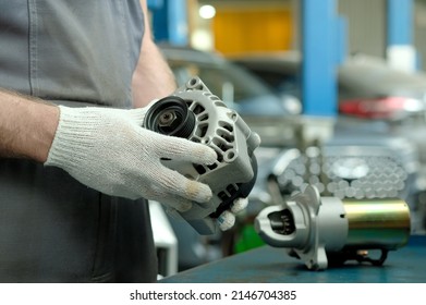 Spare parts. Elements of the electrical system of the car engine. The car generator is in the hands of an auto mechanic. There is a car starter on the desktop. Repair and maintenance of the car in the - Shutterstock ID 2146704385