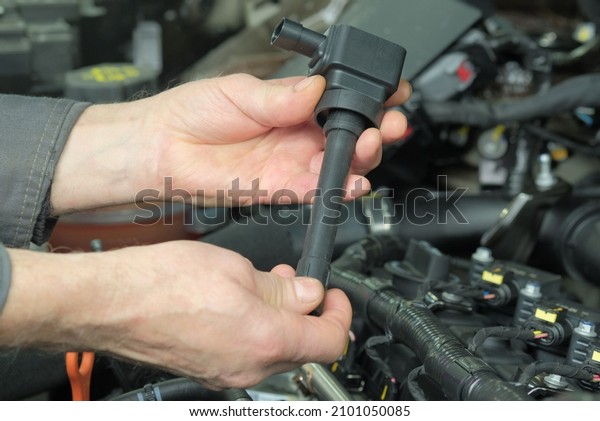 Spare parts. The ignition coil is in the hands\
of an auto mechanic. Installing a new ignition coil on the car\
engine in a car service\
station.