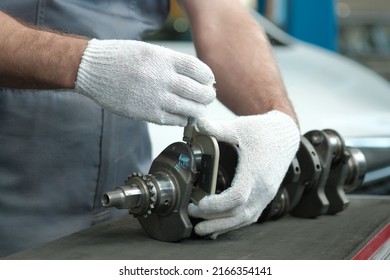 Spare parts for a passenger car. The crankshaft.  An auto mechanic measures the crankshaft crank neck with a micrometer. Car engine repair.