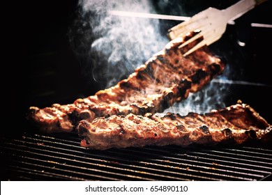 Spare ribs cooking on barbecue grill for summer outdoor party. Food background with barbecue party