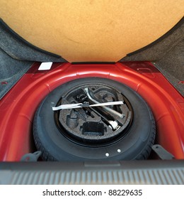 Spare Tire In The Trunk Of A Red Modern Car. Useful Photograph For Our Repair Brochure, Auto Service  Advertising Or Flyer.