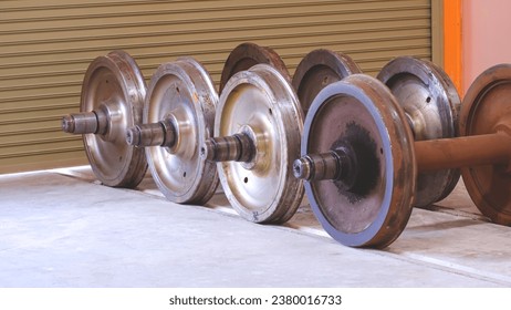 Spare wagon railway wheels with axle on the floor inside of repair depot workshop
