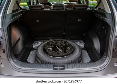Spare wheel in the trunk of a modern car. Jack lifting and a spare tire in rear of car. - Shutterstock ID 2071926977