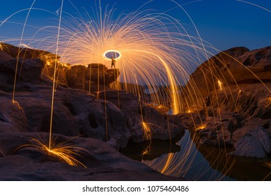 Spark fire swirl from steel wool over the rocks and reflection in water at night, Sam Phan Bok, Thailand. - Powered by Shutterstock