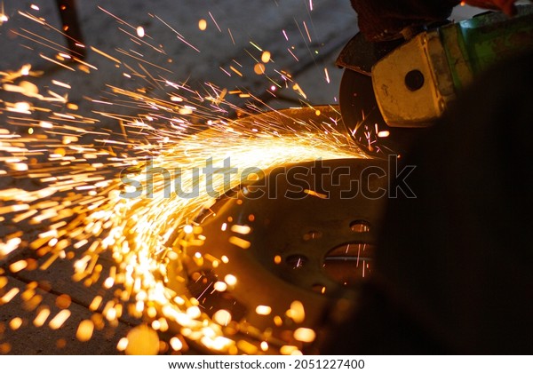 Spark grinder. Hot white sparks when cutting steel\
material. Industrial worker cutting metal with a grinder. Lots of\
glowing sparks 