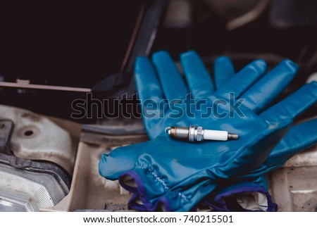 Spark plug. Car candles lie on gloves, in background service center