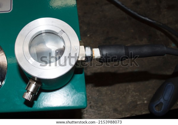 The spark\
plug connected by means of a high-voltage wire is installed in the\
pressure chamber of the green stand for checking the spark plugs of\
gasoline internal combustion\
engines