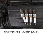 Spark plugs with worn electrodes. Used, burned four spark plugs. Electrical ignition engine spare parts, spark plug on black background. Ignition system problem. Replacing spark plugs. Selective focus