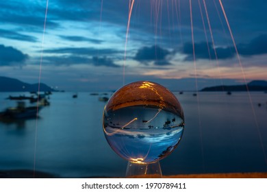 The sparkle of burning steel wool is the red line in the glass ball in twilight. With the sea and the morning light as a background.