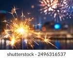 Sparkler with blurred fireworks light up the night sky during New Year celebration