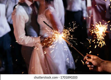 Sparkler in hands on a wedding - bride, groom and guests holding lights