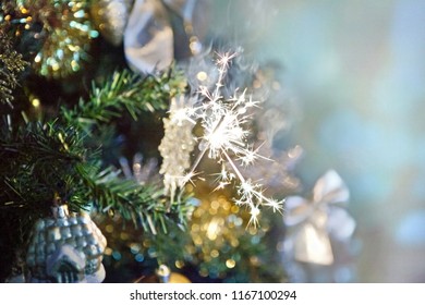 Sparkler on Christmas tree with blurred background and Christmas lights