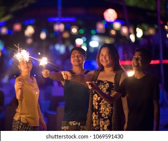 Sparklers with group of friends having fun for celebration and hand holding a burn sparkler light and playing together. Cinema film tone with grain. Dark concept. - Shutterstock ID 1069591430