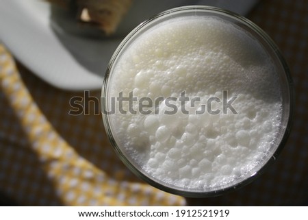 
Sparkling buttermilk in glass cup on yellow white checkered tablecloth.