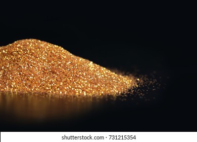 Sparkling gold glitter powder on black background - Shutterstock ID 731215354
