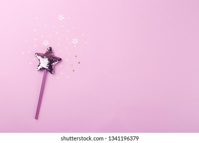 Sparkling magic wizard wand star shape on pink background, copy space