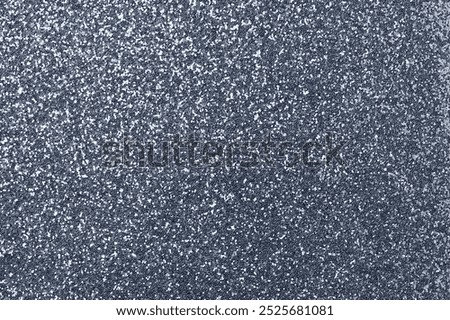 Sparkling silver background with a glittery texture. The background is filled with silver speckles, creating a shimmering silver effect. Dark blue glitter background.