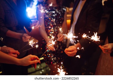 Sparkling sparklers in the hands of friends. Young people having fun with fire sparklers at night time. Holidays, vacation, relax, party and lifestyle concept. - Powered by Shutterstock