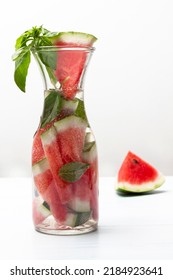 Sparkling Watermelon Water With Basil In Glass Jar. Piece Of Watermelon On Table. Close Up. White Background.