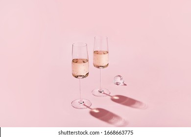 Sparkling wine glasses on colored pink background. Champagne glasses with sharp shadows. Modern, stylish color concept

