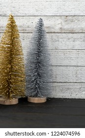 Sparkly Gold And Silver Bottle Brush Christmas Trees Against A Wooden Background, Portrait Orientation