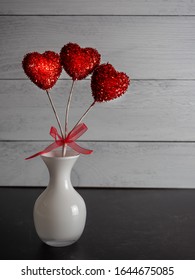 Sparkly Red Hearts On Sticks With A Red Bow In A White Glass Vase Against A Black Slate And Gray Shiplap Background, Perfect For Love Or Valentine’s Day.