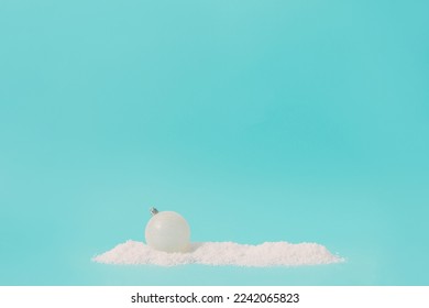 Sparkly white Christmas bauble on a bright blue background with snow. Creative winter concept. - Shutterstock ID 2242065823