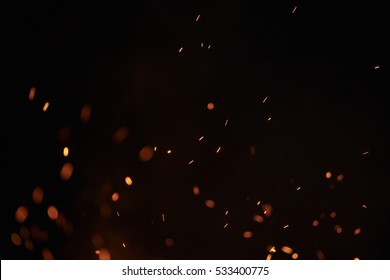sparks from bonfire over dark night environment, shallow focus