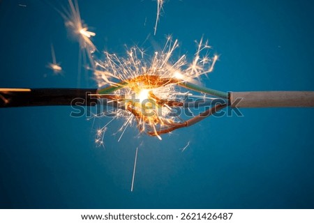 Sparks explosion between electrical cables, on deep blue background, fire hazard concept, soft focus close up