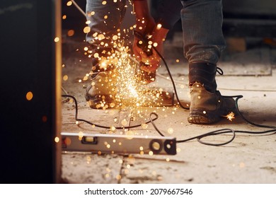 Sparks flying. Close up view of man's legs and hands with slicing tool. Working with metal.