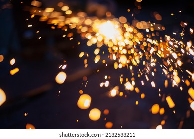 Sparks from grinding metal. Steel processing in workshop. Lights in dark. Production of parts. Cutting became grinder. Processing of welding seams.