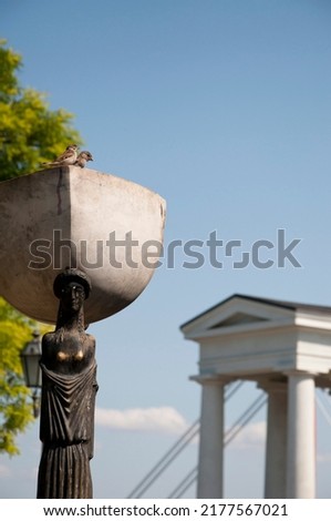 Sparrows birds sitting in stone bowl on head of female statue in Odesa, Ukraine.