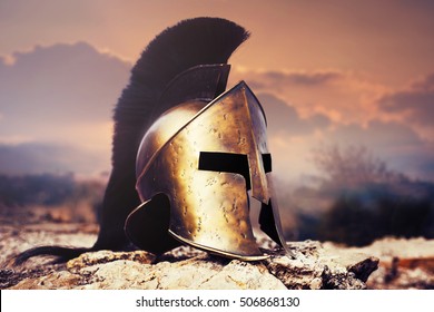 Spartan fiction helmet on rocks with sunset sky.