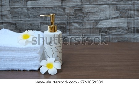 Spa-style setup with rolled white towels and a pump bottle on a wooden tray.