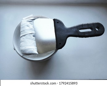 A spatula with a layer of putty on a can of putty on the windowsill before the finishing putty. Window sill repair. Advertising of renovation work. - Shutterstock ID 1792415893
