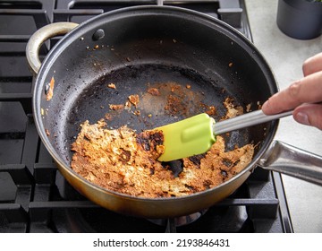 A spatula for stirring food picks off burnt food in a pan. Poor quality Teflon coated pans.