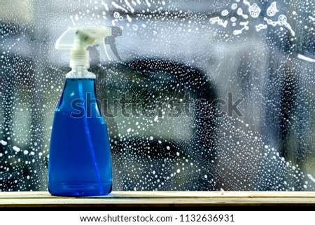 Spay glass cleaner bottle on dity glass background. 