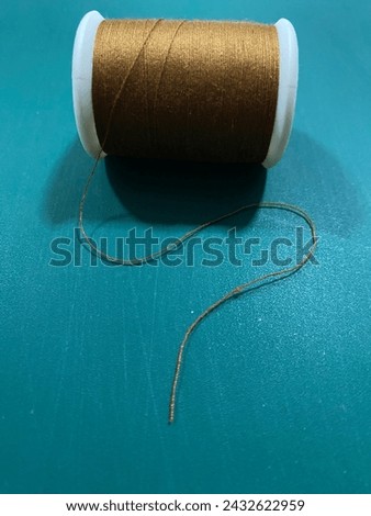 a spe of brown thread on a turquoise background