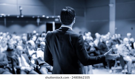 Speaker at Business Conference with Public Presentations. Audience at the conference hall. Entrepreneurship club. Rear view. Panoramic composition. Blue toned greyscale. - Powered by Shutterstock